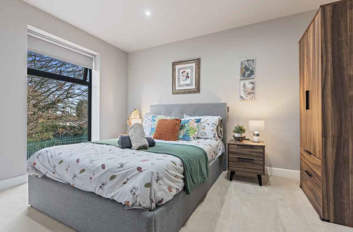 Bedroom with a grey upholstered bed and wooden wardrobe